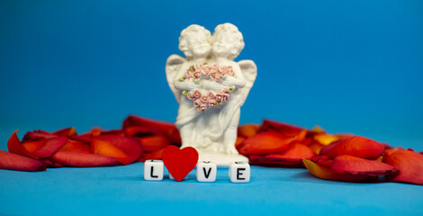 Two cute angels and the word love on the background of rose petals .Valentine's Day. Postcard for the holidays