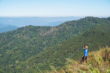 Fototapeta na wymiar A female traveler hiking and sitting on mountain peak, looking at a beautiful view