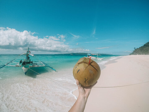 Person holding coconut drink on sea shore