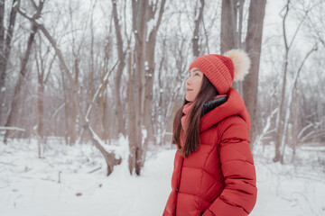 Fototapeta na wymiar Asian woman happy outdoors in winter nature forest. Portrait of young multiracial ethnicity lady wearing red hat and coat.