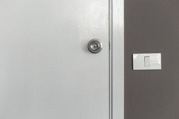 Light switch on the white wall next to the door