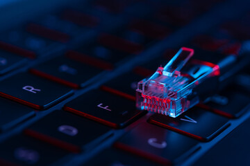Close-up view of internet network cable on a laptop keyboard with neon lights. Concept of modern IT technology. Internet switch.