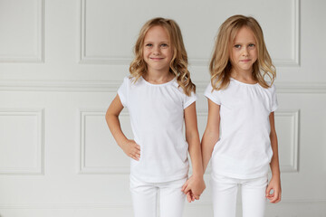Two little kids girls in white clothes isolated on white background. Childhood concept. Twin girls they hold hands.