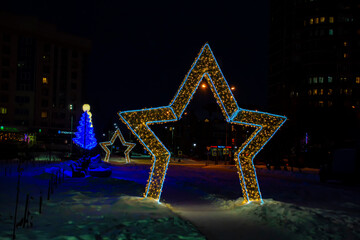 New Year's installation in form of star at night in city. One in the foreground, the other in the...