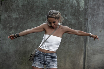 Beautiful girl wearing white t-shirt and jeans shorts posing against the street city wall background Urban style woman in fashion clothes