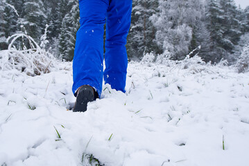 Fototapeta na wymiar man hiking in winter forest by snow in hiking shoes boots. Winter hiking.