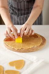 The process of preparing dessert for Valentine's Day. Women's hands cut heart-shaped cookies from dough.