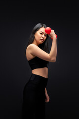 asian woman in black sportive wear with dumbbells, pumping arm muscles, isolated on black studio background. sport and healthy lifestyle concept