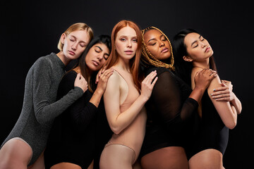 female models leaned on each other, tolerant and friendly. diverse women in bodysuits posing at camera, european african asian natural beauty