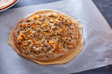 Step-by-step preparation of the festive Russian Kurnik pie, assembling a puff pie with fillings, step 4 - laying out the second filling with fried chicken and carrots on pancakes, shorizontal © Анна Журавлева