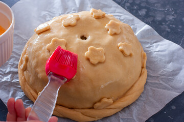 Step-by-step preparation of the festive Russian Kurnik pie, assembling a puff pie with fillings, step 7 - decorating Kurnik with dough flowers before baking and smearing with a raw egg, horizontal © Анна Журавлева