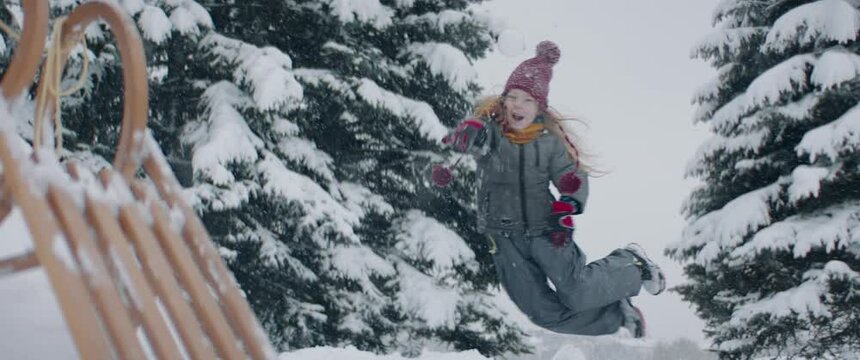 Funny little kid boy participating in snow brawl, jumping and throwing a snowball. Fun winter games outside. 120 FPS slow motion shot.