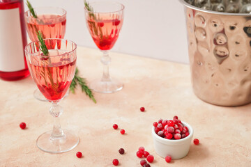 Glasses of champagne cocktail with cranberry and rosemary on color table