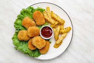 Tasty nuggets, ketchup and french fries in plate on light background