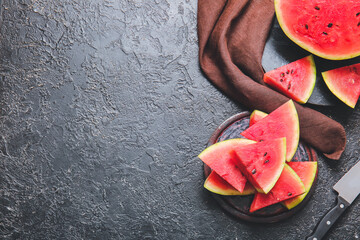 Plate with slices of ripe watermelon on dark background