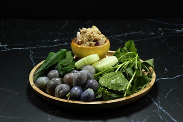 Pile of mixed fresh vegetable serving with spicy fish paste on the wooden plate. Famous appetizer menu in Asia restaurant. 