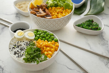 Bowls with tasty rice, eggs and vegetables on light background