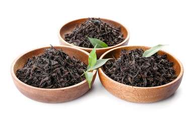 Dry black tea leaves in bowls on white background
