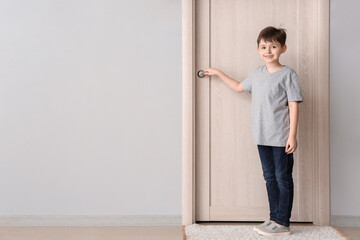 Fototapeta na wymiar Cute little boy standing near closed door