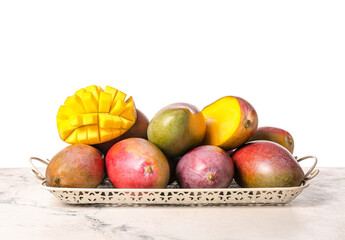 Sweet ripe mangoes on table against white background