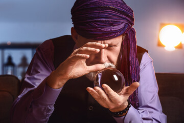 Male fortune teller with crystal ball at home - obrazy, fototapety, plakaty