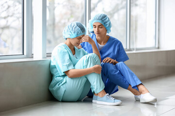 Female doctor calming her stressed colleague in clinic