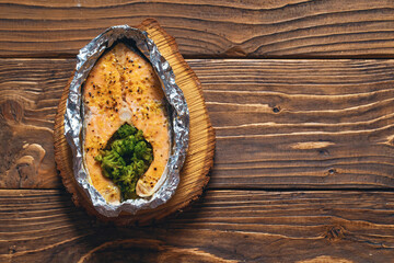 Obraz na płótnie Canvas Baked, foil-wrapped salmon steak with broccoli, seasoned with lemon zest, spices