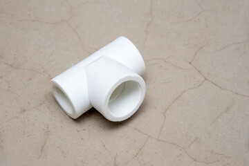 Tee T-shaped plastic, plumbing on a gray cement background, close-up, top view, copy space. High temperature soldering. Construction, renovation concept