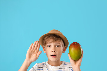 Fototapeta premium Cute little boy with fresh tasty mango on color background
