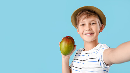 Fototapeta premium Cute little boy with fresh tasty mango on color background