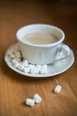 A cup of marshmallow coffee on a brown wooden table