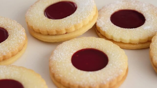 Jam cookies are on the wire plate. Female hands a making homemade biscuit shortbread cookies with jam. Kurabye cookies with raspberry jam. Christmas cookies with jam.
