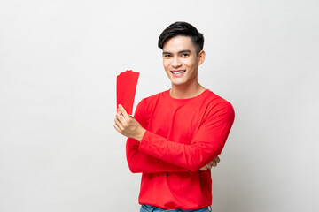 Smiling handsome Asian man holding red envelopes or Ang Pao in studio isolated gray background for Chinese new year concepts