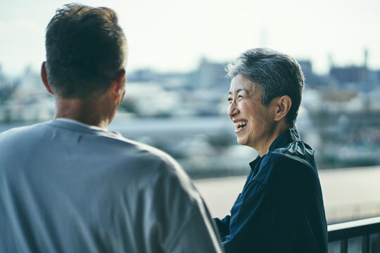 ベランダで景色を眺める笑顔の日本人シニア女性とシニア男性