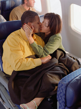Mature couple cuddling on airplane