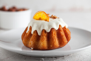 Traditional Italian rum cake with almonds. Delicious Sweet Rum Baba cake with sugar glaze on a white plate and concrete background. Traditional italian fluffy bread with cup of coffee or tea. 