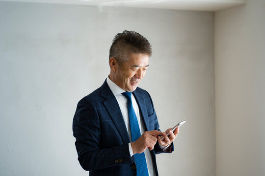 スマートフォンを見るシニア世代の日本人ビジネスマン