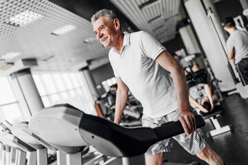 Cardio. The older man smiles and performs a cardio exercise