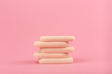Close up of stack of beige make up sponges for applying foundation, bb cream, base or concealer against bright pink background with copy space