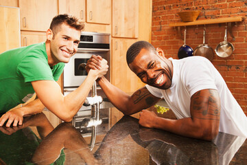 Men arm wrestling in kitchen
