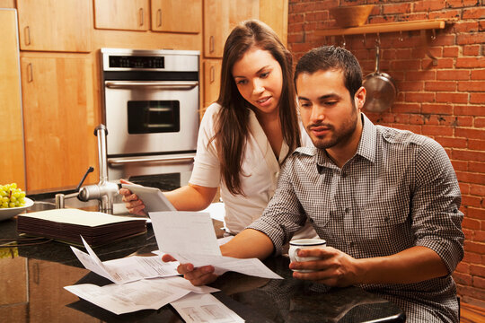 Hispanic couple looking at paperwork in kitchen