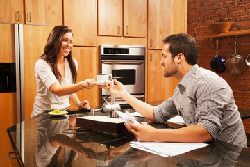 Hispanic woman handing husband coffee in kitchen