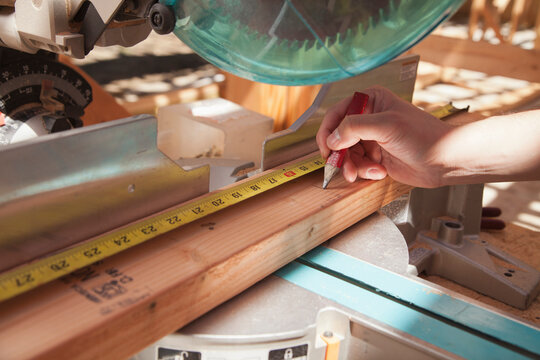 Mixed race man measuring wood on saw
