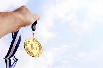 Plakat man hand raised, holding gold medal against sky. award and victory concept