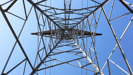 Under the electric tower, the tower for high voltage cables on the background of the clear blue sky. Selective focus