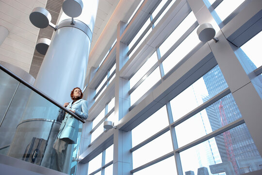 Caucasian businesswoman leaning on railing in lobby