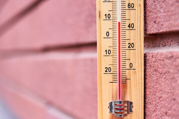 Close-up photo of household alcohol thermometer against a pink wall showing temperature in degrees...