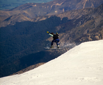 Snowboarder leaping off side of ledge of snowy Mount Hutt 