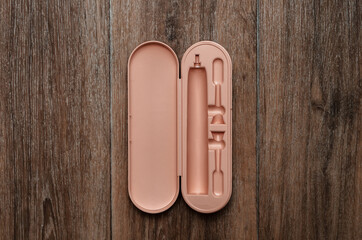 empty pink plastic case for electric toothbrush on wooden background