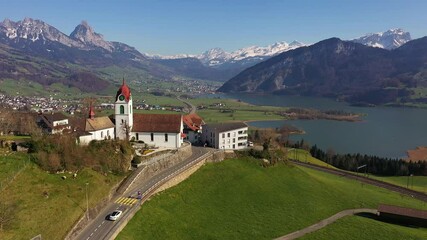 Aerial footage of the idyllic Steinerberg village on the road between Arth and Schwyz with the Lauerzersee lake and the 
Grosser Mythen mountain peak in the background in Central Switzerland.